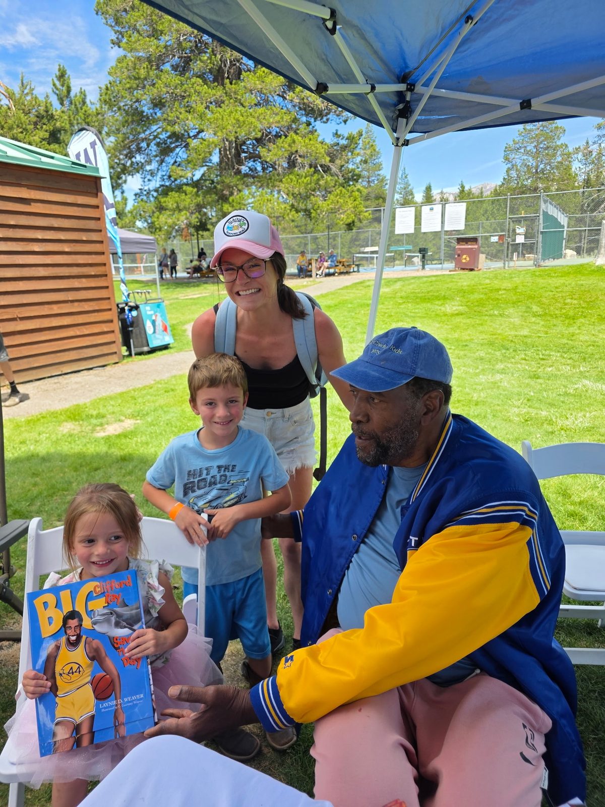 Coach Ray in a Warriors jacket with a family at an outdoor event