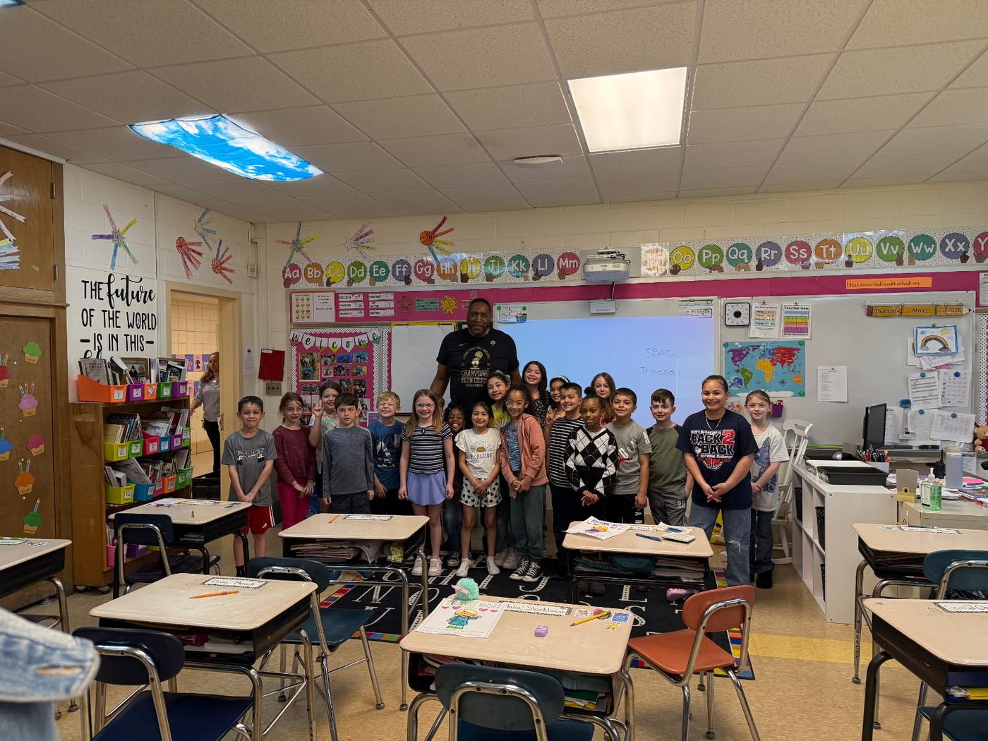 Coach Ray standing with an elementary class in their classroom