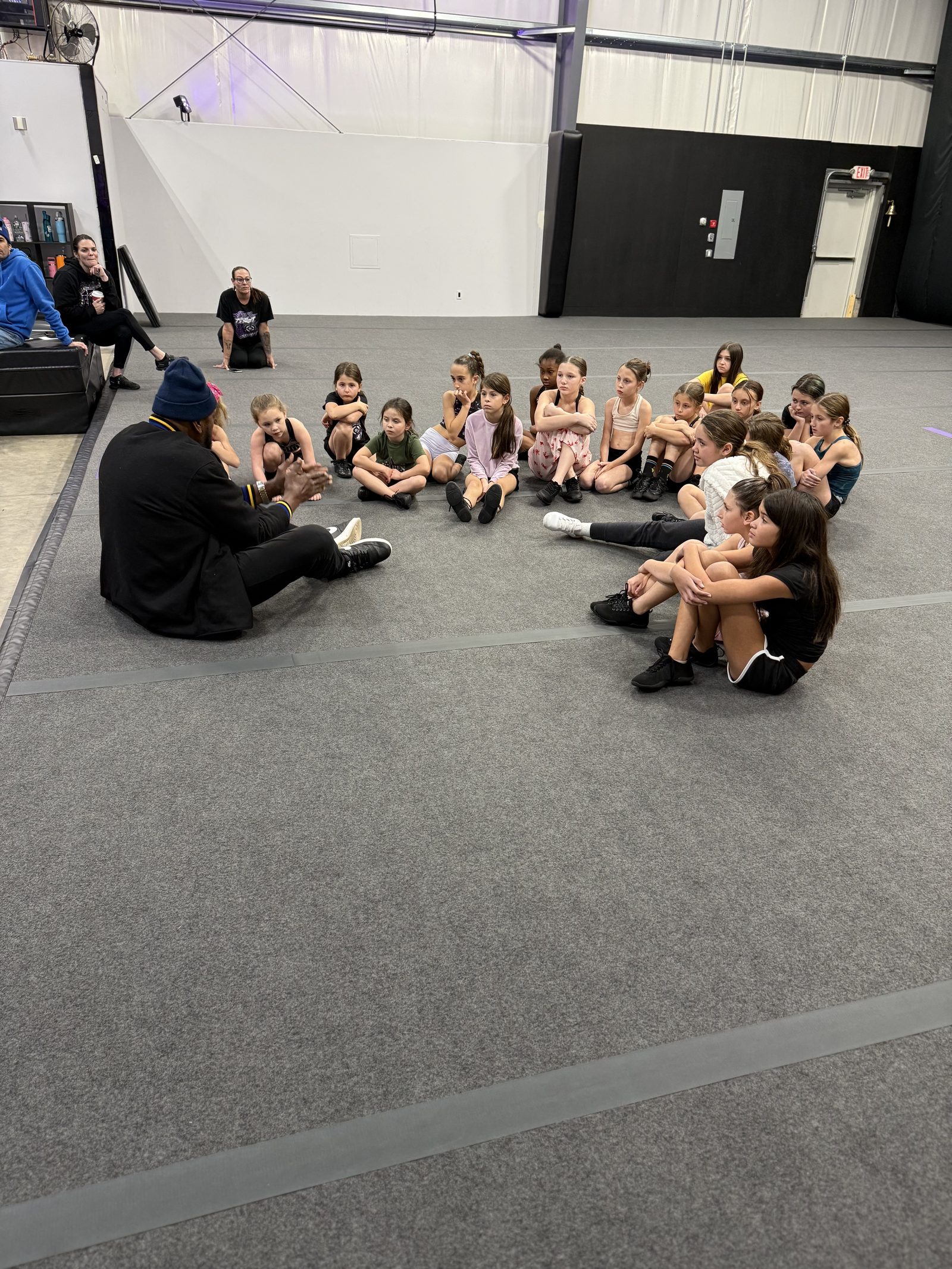 Coach Ray talking with a circle of kids in a gym
