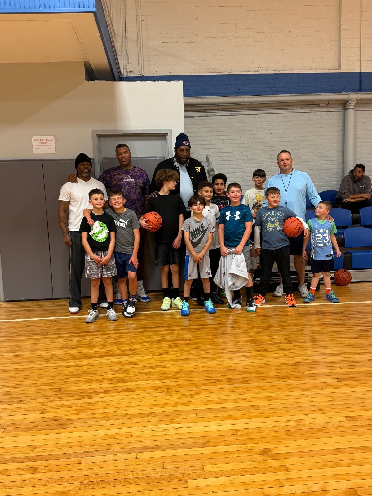 Kids with basketballs in a school gym with Coach Ray