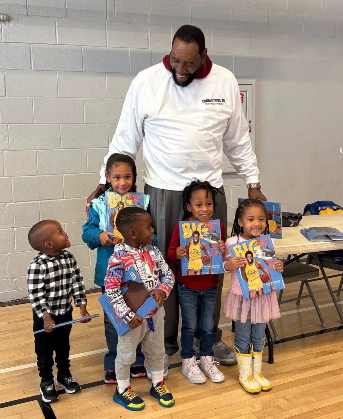 Coach Ray with four small kids, each holding a copy of Big Clifford Ray Saves the Day