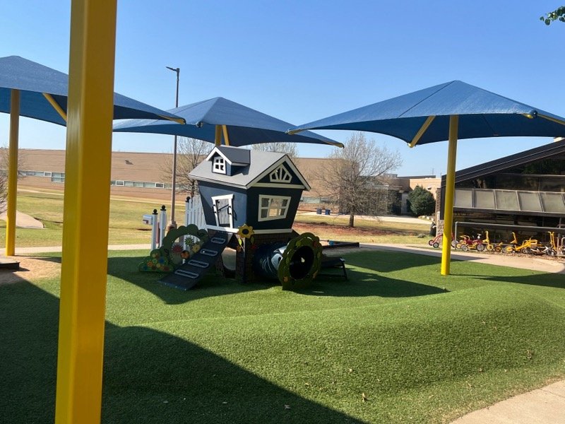 A playhouse under shade canopies on a school playground